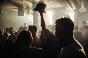 Vibrant crowd enjoying a lively night in a dimly lit club with music and dancing.